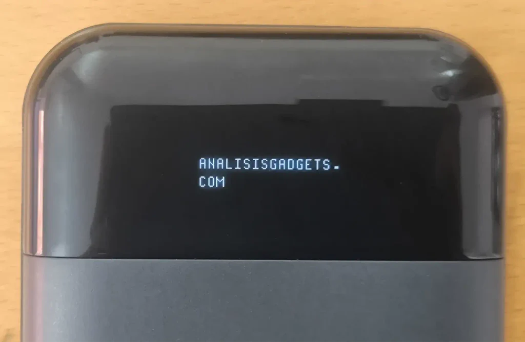Pantalla OLED del GL.iNet Mudi V2 mostrando el texto personalizado ANALISISGADGETS.COM