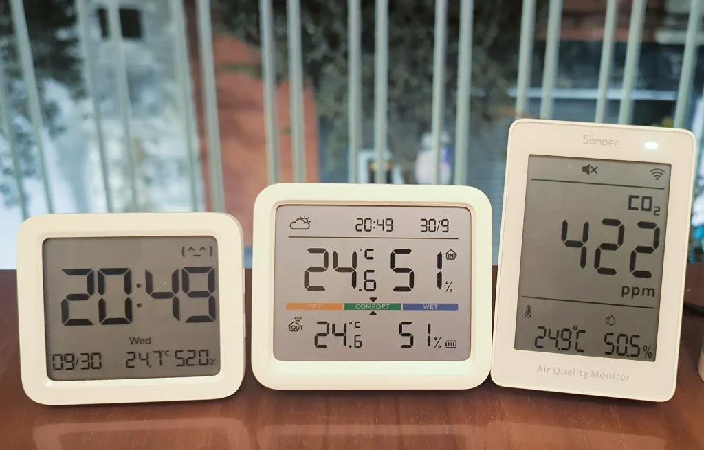 SONOFF AirGuard CO2 junto a un Xiaomi Temperatura y Humedad 3 y un SwitchBot Meter Pro, comparando temperatura y humedad; el SONOFF marca 422 ppm de CO₂, 24,9 °C y 50,5 %