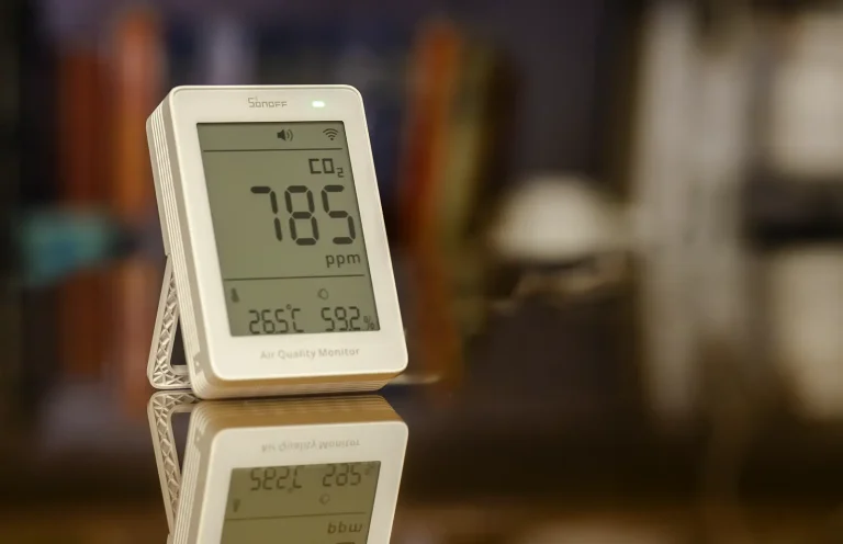 SONOFF AirGuard CO2 sobre una mesa, mostrando 785 ppm de CO₂, 26,5 °C y 59,2 % de humedad, con el indicador de calidad del aire en verde